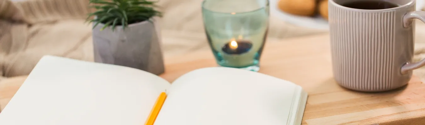 photo showing notebook with pencil, candle, and plant